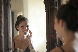 Facial Masking women in mirror applying cream